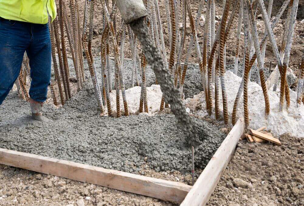 Worker pouring concrete with pump tube