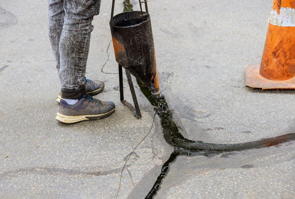 Men sealing asphalt driveway cracks
