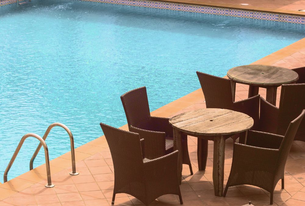 table and chairs on the side of a stamped concrete pool deck