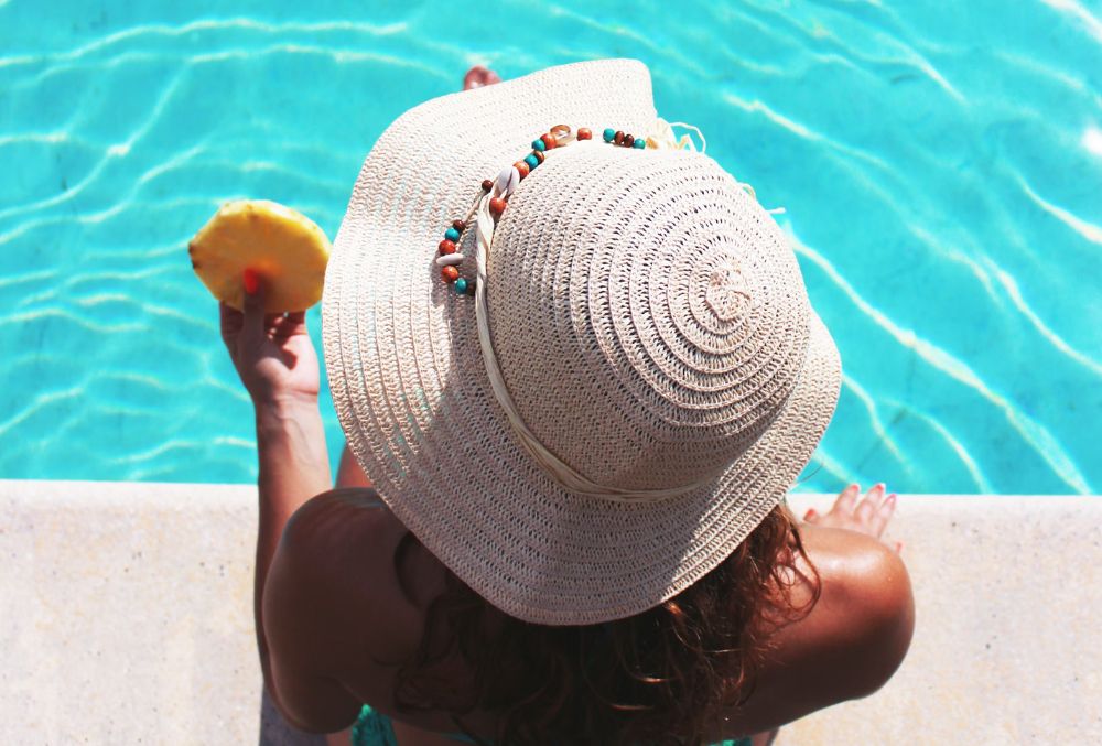 lady enjoying her pineapple on a concrete pool deck
