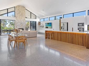 Interior view of a home with polished concrete flooring, featuring stairs and a modern kitchen counter.